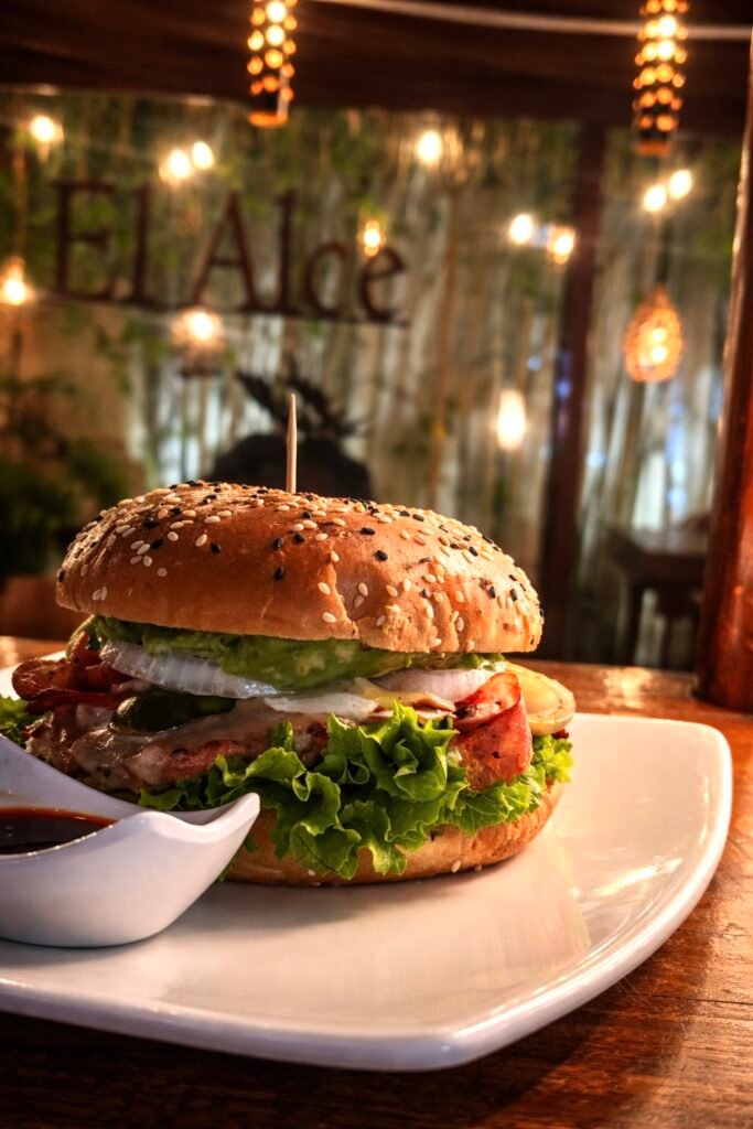 Sal de la rutina Hamburguesas con tocino crujiente y guacamole a lado de salsa macha en un ambiente cálido y acogedor en Puebla