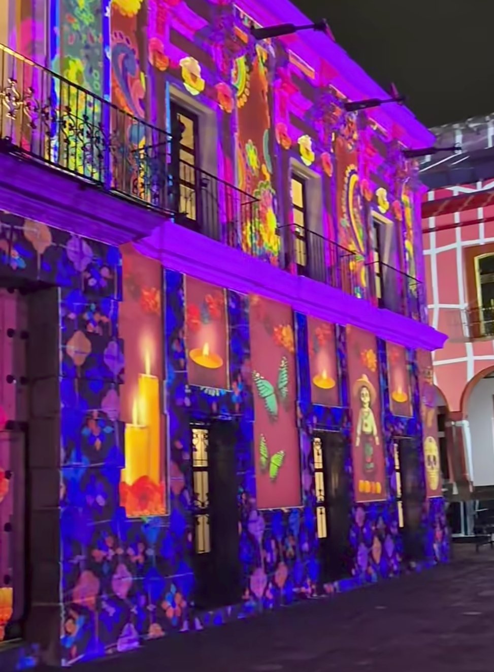 Proyección de luces con motivos mexicanos del Día de Muertos en la fachada del Teatro Principal en Puebla, evento al aire libre.