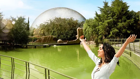 Familia Mujer con los brazos abiertos y expresión de felicidad frente a un domo cerca de un lago de color verde, Naturaleza y Aire libre en Familia, pareja o amigos.